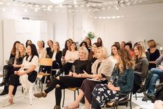 a group of women sitting next to each other in front of a room full of people