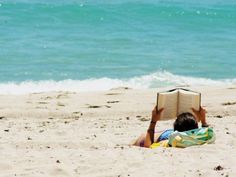 a person sitting on the beach reading a book