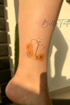 an orange butterfly tattoo on the ankle with words below it that read blythe