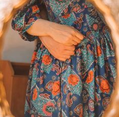 a close up of a person wearing a blue dress with orange and green flowers on it