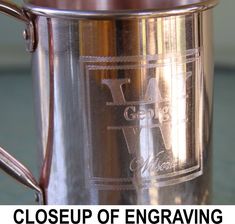 closeup of engraving on the side of a large metal coffee mug with handle and handles