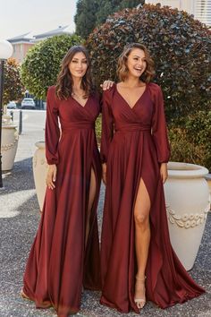 two women standing next to each other wearing long dresses with thigh high slits on the side