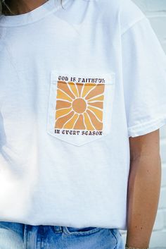 Product Details: Embrace the power of faith with our God Is Faithful Pocket Tee. This white tee boasts a vibrant sunshine detail and features the inspiring message "God is faithful in every season". With a comfortable fit and a Christian theme, this tee is perfect for spreading positivity and uplifting spirits. Product Material: 100% Cotton Hope's Go-To Outfit: "I love pairing this tee with a comfy pair of leggings or biker shorts to go run errands in!" Sizing Info: Model is 5'1" and wearing siz Inspirational White T-shirt For Everyday, White Inspirational Relaxed Fit T-shirt, Inspirational White Tops For Everyday Wear, White Inspirational Everyday T-shirt, Inspirational White T-shirt, Everyday Inspirational White T-shirt, Inspirational White Cotton T-shirt, God Is Faithful, Spreading Positivity