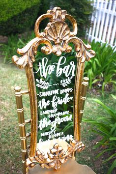 a gold chair with a sign on it sitting in the grass next to some bushes