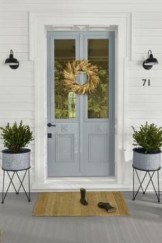 a front door with two planters and a wreath on it