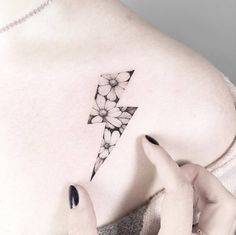 a woman with a flower tattoo on her back shoulder and left arm, holding onto the side of her chest