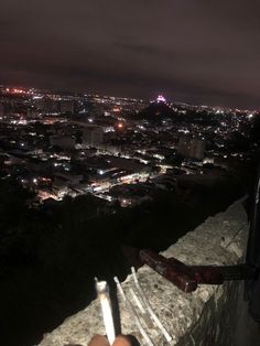 someone is sitting on the edge of a wall at night