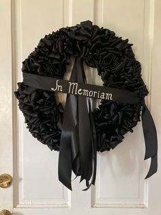 a black wreath with the words in memo written on it and a ribbon hanging from the front door