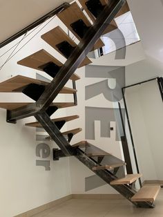 a wooden stair case next to a white wall with black lettering on it and a bench underneath