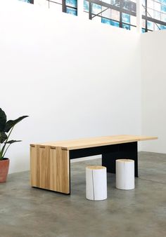 a wooden bench sitting next to two white vases on top of a cement floor