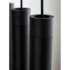 two black vases sitting next to each other on top of a wooden table with a straw sticking out of it