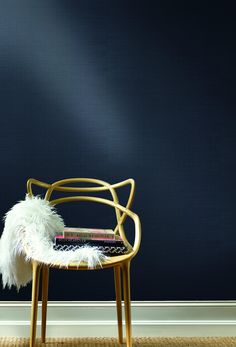 a chair with a book on it in front of a dark blue wall and carpet