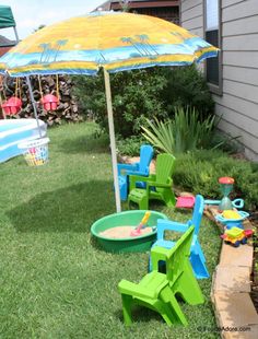 an umbrella and lawn chairs are in the grass near a pool with toys on it