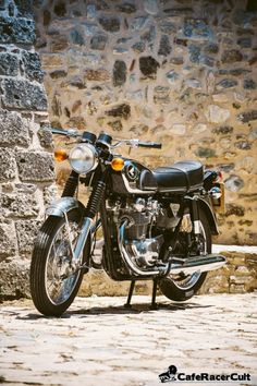 a black motorcycle parked next to a stone wall