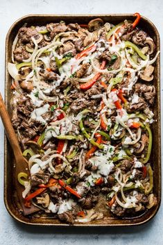 a casserole dish with beef, peppers, onions and cheese on top is ready to be eaten