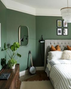 a bed room with a neatly made bed and green walls