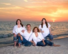 a family sitting on the beach at sunset