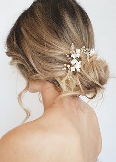 a woman wearing a hair comb with flowers in it's back half - up