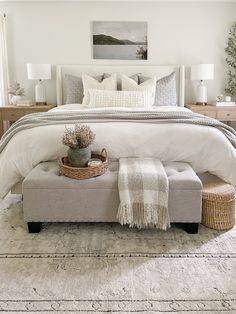 a bedroom with a large bed and white linens on the pillows, along with a basket full of plants