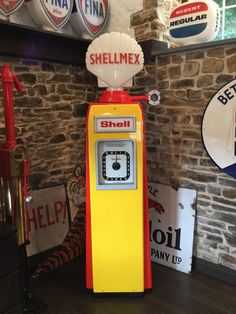 an old fashioned gas pump sits in the corner of a room with signs on the wall