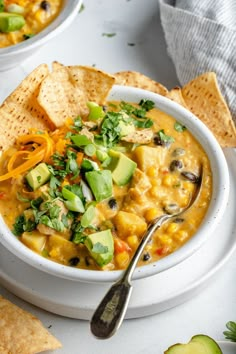 two bowls of soup with tortilla chips and avocado on the side