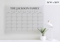 a white desk with a black and white calendar on the wall next to a potted plant