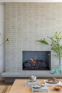 a living room with a fire place and vases on the table in front of it