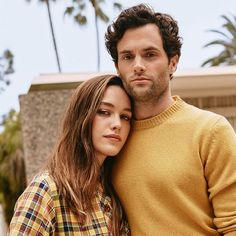 a man and woman standing next to each other with palm trees in the back ground