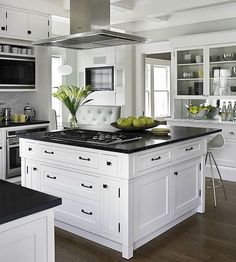 a large kitchen with white cabinets and black counter tops, an island in the middle