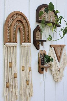 two wall hangings on the side of a building with plants in vases next to them