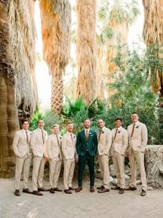 a group of men standing next to each other in front of trees and palm trees