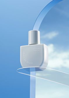 a bottle of cologne sitting on top of a glass shelf in front of a blue sky