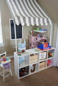 a child's play room with toys and bookshelves on the floor in front of a striped awning