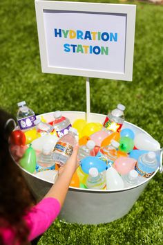 a bucket filled with lots of different types of water and plastic bottles next to a sign that says hydration station