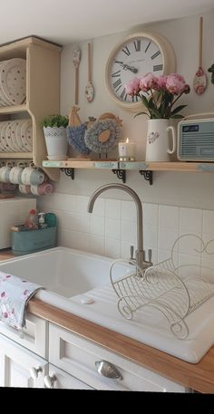 a white kitchen sink sitting under a clock