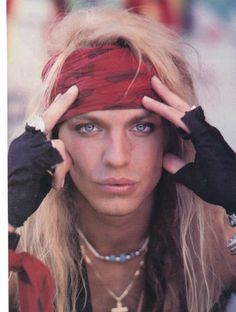 a woman with long hair wearing a bandana and holding her head in front of her eyes