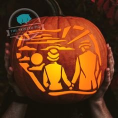 two people holding up a carved pumpkin with an image of a family on it and the words, the painted big