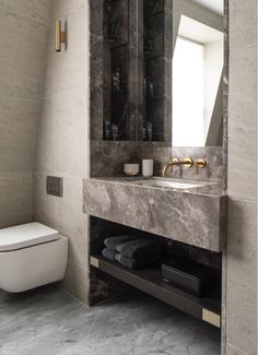 a bathroom with a toilet, sink and mirror in it's center wall next to a window