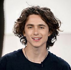 a close up of a person wearing a black shirt and a necklace on his neck