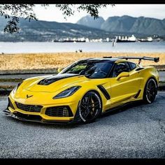 a yellow sports car parked in front of a body of water