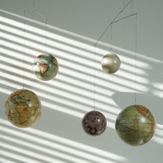 three globes hanging from the ceiling in front of a white wall with shadows on it