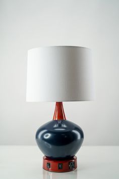 a blue and red table lamp with a white shade