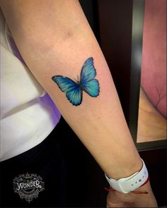 a blue butterfly tattoo on the arm