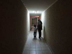 a woman and child walking down a long hallway