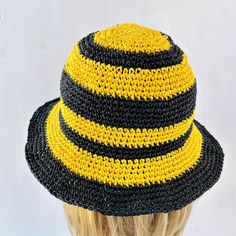 a crocheted hat with black, yellow and white stripes on the brim