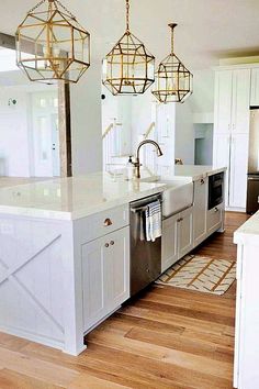 a kitchen with white cabinets and gold chandeliers