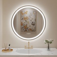 a bathroom sink with a round mirror above it and a painting on the wall behind it