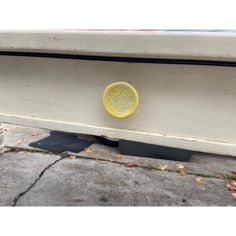 a yellow button on the side of a white bench