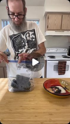 a man standing in front of a kitchen counter holding a plastic bag filled with food