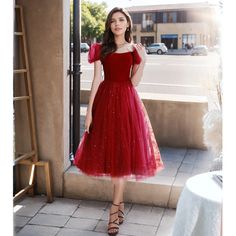 a woman in a red dress is standing outside